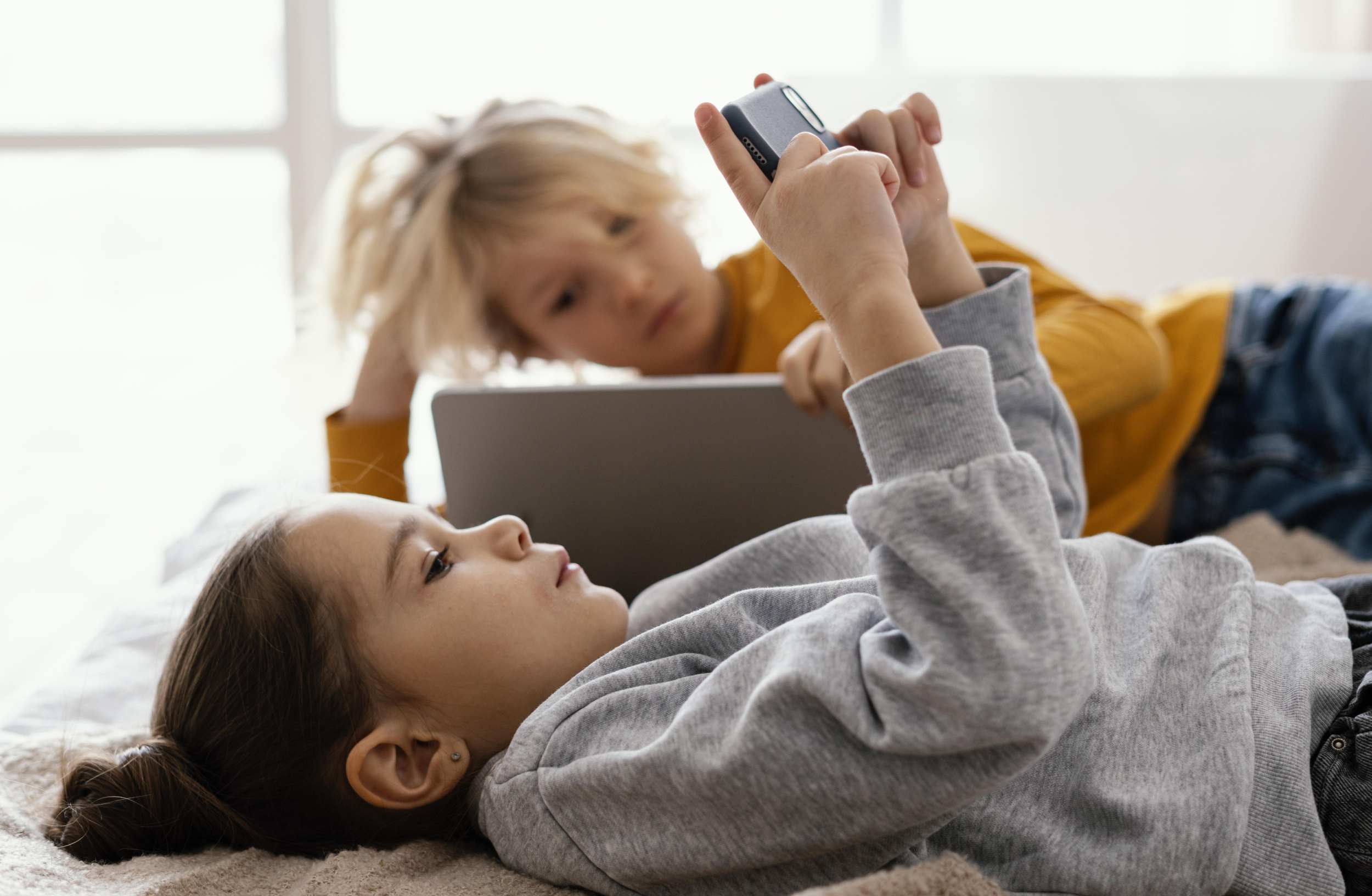 1 siblings-bed-playing-mobile-tablet.jpg